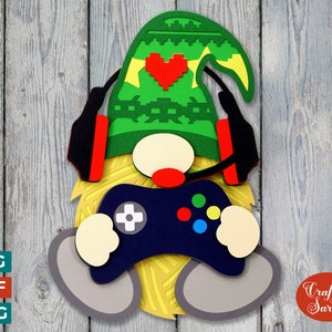 May include: A green gnome wearing a red and black headset and a green hat with a pixelated heart. The gnome is holding a blue video game controller with red, blue, yellow, and green buttons.