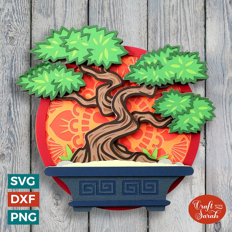 May include: A papercraft bonsai tree with a brown trunk and green leaves, set against a red and orange circular background with a decorative pattern. The tree is in a blue pot with a geometric design.