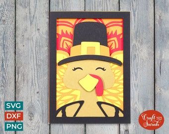 May include: A papercraft Thanksgiving card featuring a turkey wearing a pilgrim hat. The turkey is brown with a yellow beak and red wattle. The background is a red and yellow mandala design. The card is framed in black.
