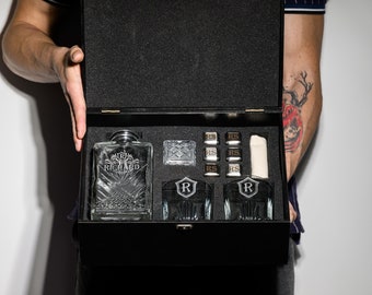 May include: A black wooden box with a clear glass decanter, two glasses, and ice cubes. The decanter has the word "RICHARD" etched on it. The glasses have a gold "R" on them. The box is open and the contents are visible.