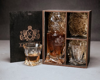 May include: A wooden box set with a glass decanter and two glasses. The decanter and glasses are engraved with the letter "K" and the word "KASYNETS". The box is lined with brown paper.