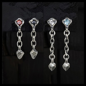 Può includere: Quattro paia di orecchini pendenti in argento con pietre preziose di diversi colori: rosso, nero, trasparente e azzurro. Ogni orecchino presenta una parte superiore a forma di diamante, una catena e un pendente inferiore sfaccettato. Gli orecchini sono esposti su sfondo nero.