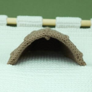May include: A brown knitted fabric dome shaped like a small house or tent.