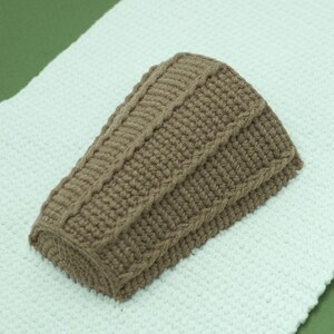 May include: A brown knitted hat with a cable knit pattern.