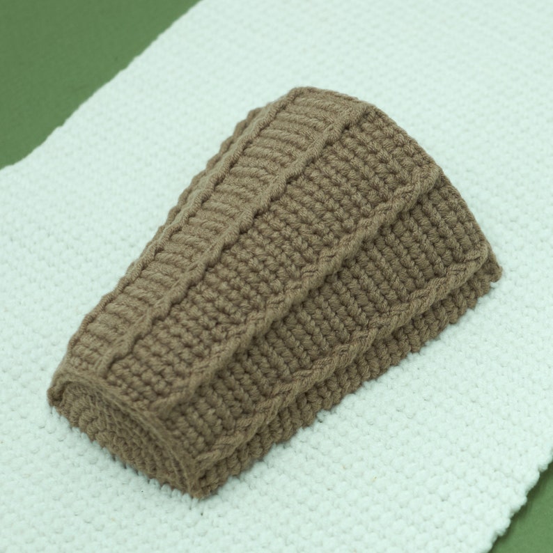 May include: A brown knitted hat with a cable knit pattern.