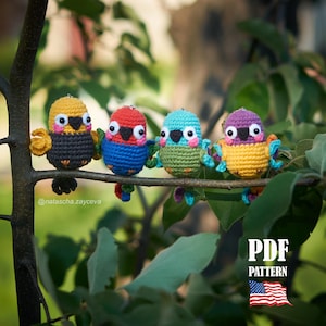 May include: Four colorful, crocheted bird ornaments perched on a tree branch. Each bird has a unique color scheme: yellow and black, red and blue, teal and green, and purple and yellow. The birds have large eyes and small wings. The image includes the text "PDF PATTERN".