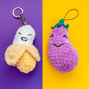 May include: Two crocheted plush toys, a banana and an eggplant, with smiling faces. Both toys have a loop for hanging.