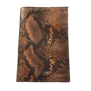 May include: A rectangular passport holder featuring a brown and black snakeskin pattern. The accessory has a textured surface with a repeating scale design and visible stitching along the edges, providing a structured and flat appearance.