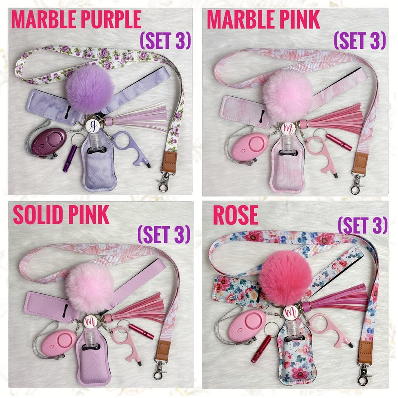 May include: Four sets of keychains with a pink or purple hand sanitizer bottle, a small keychain alarm, a keychain with a letter charm, a tassel, and a key ring. The keychains are attached to a lanyard with a floral pattern. The lanyards are labeled "Marble Purple (Set 3)", "Marble Pink (Set 3)", "Solid Pink (Set 3)", and "Rose (Set 3)".