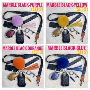 May include: Four keychains with different colored pom-poms, each with a black and white marble pattern lanyard, a small hand sanitizer bottle, a whistle, a key ring, and a small tool. The pom-poms are purple, yellow, orange, and blue.