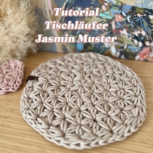 Può includere: Un runner da tavolo in crochet beige con un motivo a forma di stella. Il testo "Tutorial Tischläufer Jasmin Muster" è visibile sopra il runner. Il testo "@iraknithome" è visibile sotto il runner.
