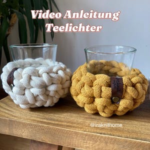 Könnte beinhalten: Zwei gehäkelte Kerzenhalter in Weiß und Gelb, mit Glas-Teelichthaltern im Inneren. Die Halter haben Lederanhänger mit dem Text "Handmade Home". Die Kerzenhalter stehen auf einer Holzoberfläche.