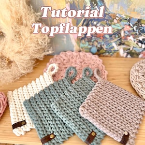 Könnte beinhalten: Eine Anleitung zum Häkeln von Topflappen. Das Bild zeigt vier gehäkelte Topflappen in verschiedenen Farben: weiß, hellblau, rosa und braun. Die Topflappen haben oben eine Schlaufe zum Aufhängen.