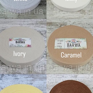 May include: Six spools of cotton elastic in different colors: white, milky white, ivory, caramel, melon, and latte. Each spool has a label with the word "BARWA" and the color name.