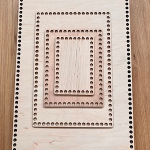 Könnte beinhalten: Drei quadratische Holzrahmen mit abgerundeten Löchern an den Rändern. Die Rahmen sind ineinander verschachtelt, wobei der größte Rahmen außen und der kleinste Rahmen innen liegt.