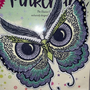 May include: An embroidered patch in the shape of an owl with butterfly wings. The patch features a detailed design with shades of blue, green, yellow, and white. The text "Pink" is visible in the upper left corner.