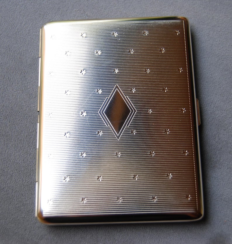 May include: Silver cigarette case with a diamond pattern and a star design.