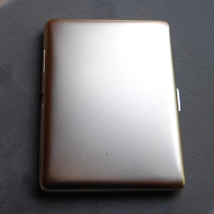 May include: A silver metal cigarette case with a smooth, brushed finish.