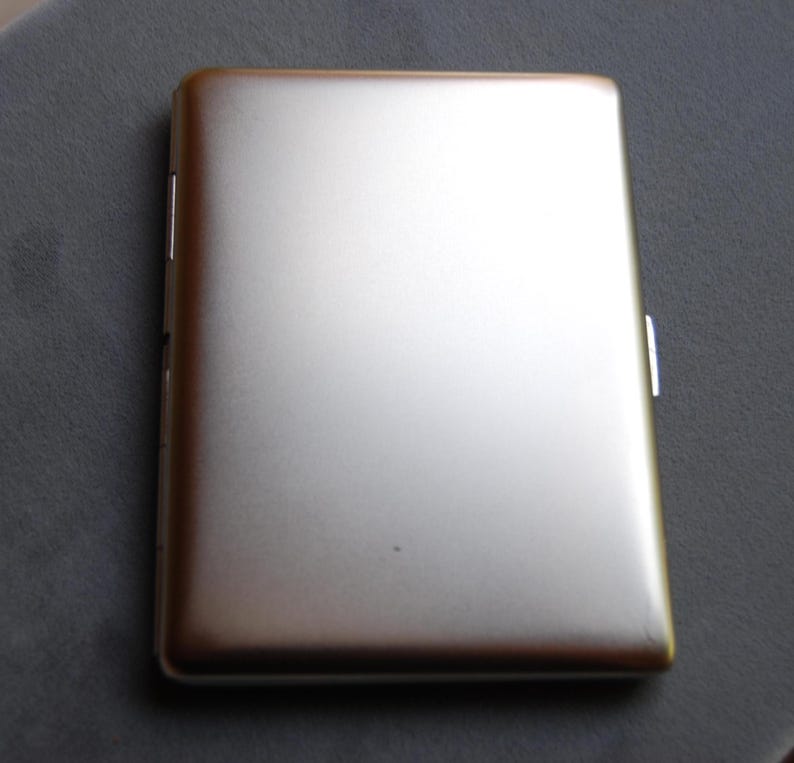 May include: A silver metal cigarette case with a smooth, brushed finish.