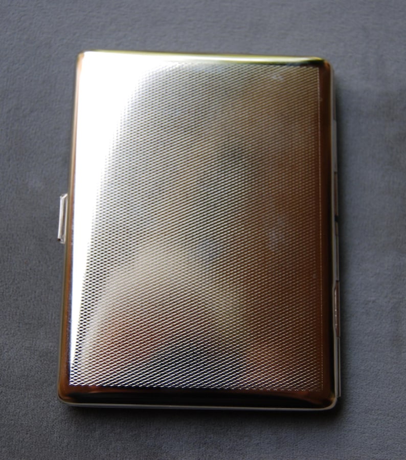 May include: A silver cigarette case with a textured surface.