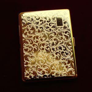 Peut inclure: Un &eacute;tui &agrave; cigarettes en or avec un motif floral orn&eacute;.