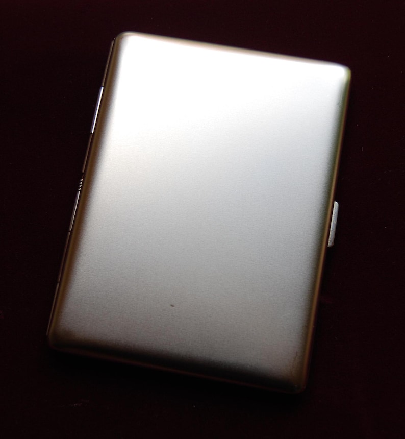 May include: A silver metal cigarette case with a smooth, brushed finish.