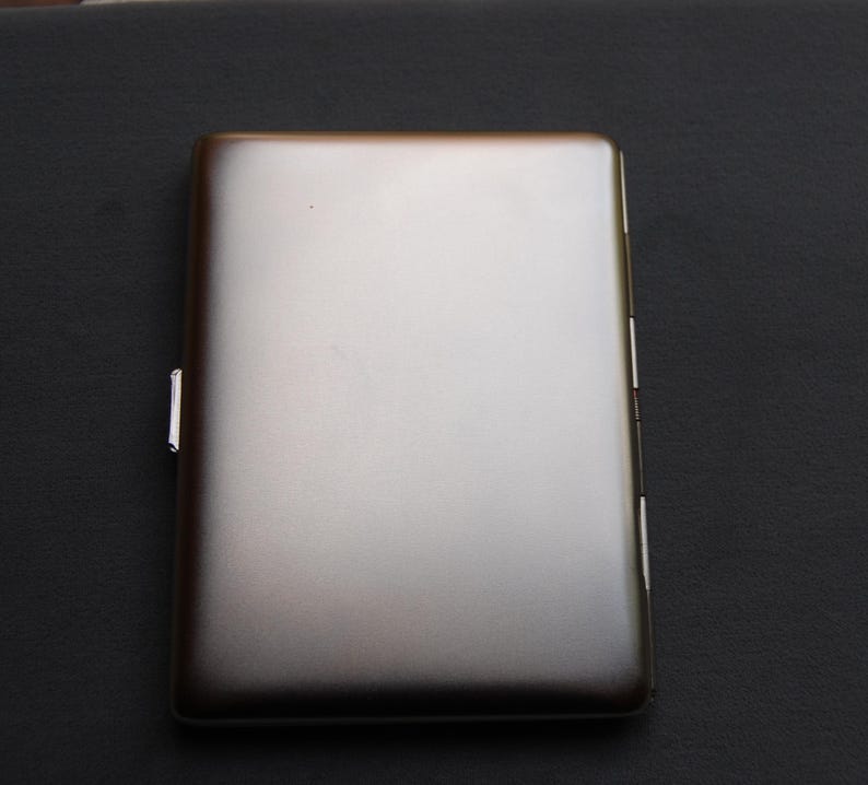 May include: A silver cigarette case with a smooth, metallic finish.