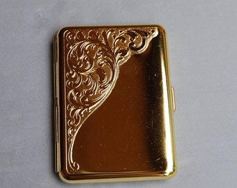 Könnte beinhalten: Ein goldenes Zigarettenetui mit einem verzierten, gravierten Design.