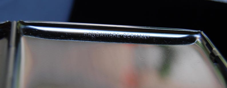 May include: Close-up of a silver metal container with the inscription "Hansaware Germany" on the edge.