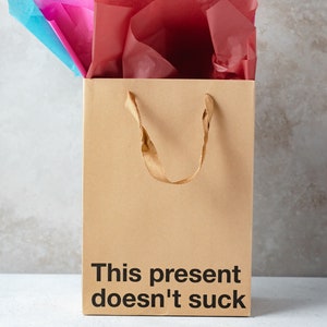 A funny gift bag made from eco-friendly brown kraft paper with "This present doesn't suck" written on the front