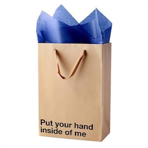 A brown paper shopping bag with blue tissue paper and the text "Put your hand inside of me" printed on it.