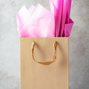 A funny gift bag made from eco-friendly brown kraft paper with "Spoiler alert: it's not a candle" written on the front