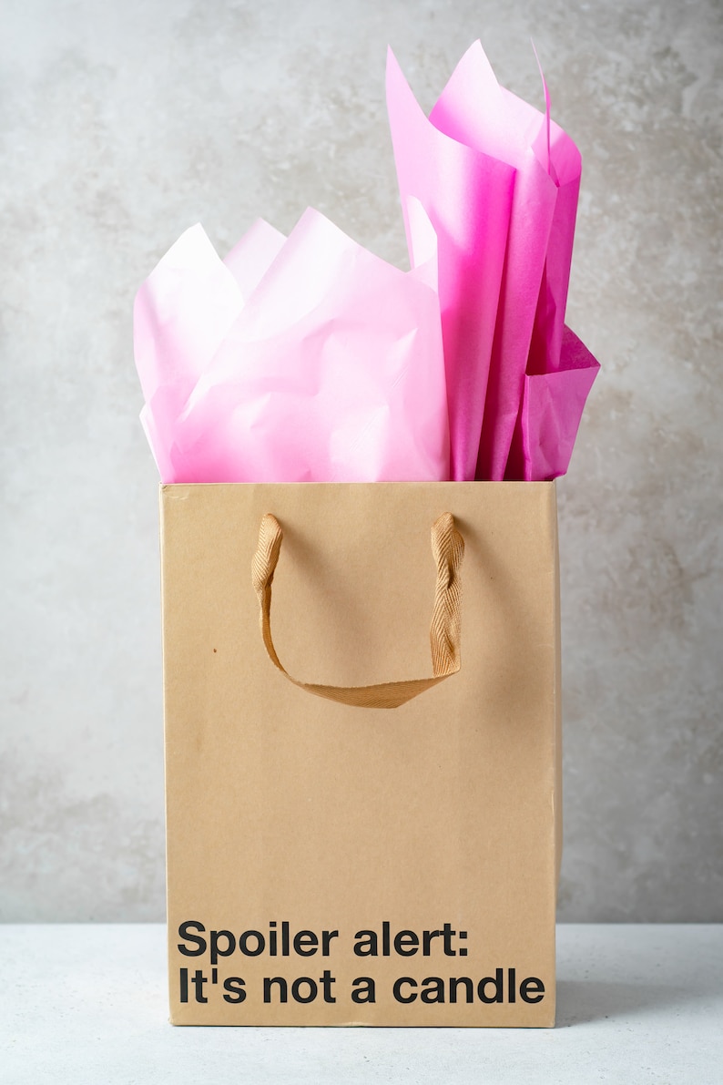 A funny gift bag made from eco-friendly brown kraft paper with "Spoiler alert: it's not a candle" written on the front