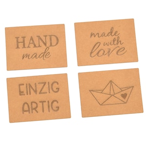 Könnte beinhalten: Vier braune Papieretiketten mit unterschiedlichen Texten und Designs. Das erste Etikett lautet "HAND made". Das zweite Etikett lautet "made with love". Das dritte Etikett lautet "EINZIG ARTIG". Das vierte Etikett hat ein Papierboot mit einem Herzen darin.