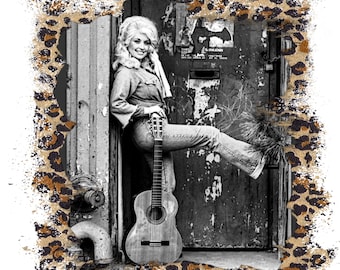 May include: A black and white graphic print featuring a portrait of a blonde person with voluminous hair, wearing a denim shirt and jeans, leaning against a weathered door while holding an acoustic guitar, framed by a brown leopard print border.