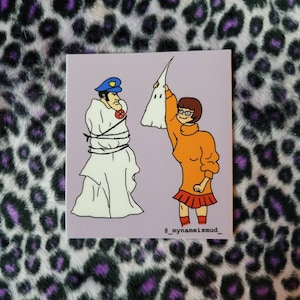 Peut inclure: Une illustration de dessin animé d'un personnage de la franchise Scooby Doo, portant un pull à col roulé orange et une jupe rouge, tenant une feuille blanche avec un visage dessiné dessus. Le personnage se tient devant un homme portant un uniforme de police et une feuille blanche enveloppée autour de lui. L'arrière-plan est de couleur violet clair. Le texte "_mynameismud_" est en bas de l'image.