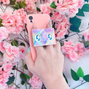 Könnte beinhalten: Eine rosa Handyhülle mit einem Aufkleber von einem Paar blauer Augen mit einem Regenbogenhintergrund.