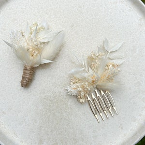 May include: Two white dried flower arrangements, one with a comb for hair and the other with a stem for pinning. Both arrangements feature white feathers and dried flowers.