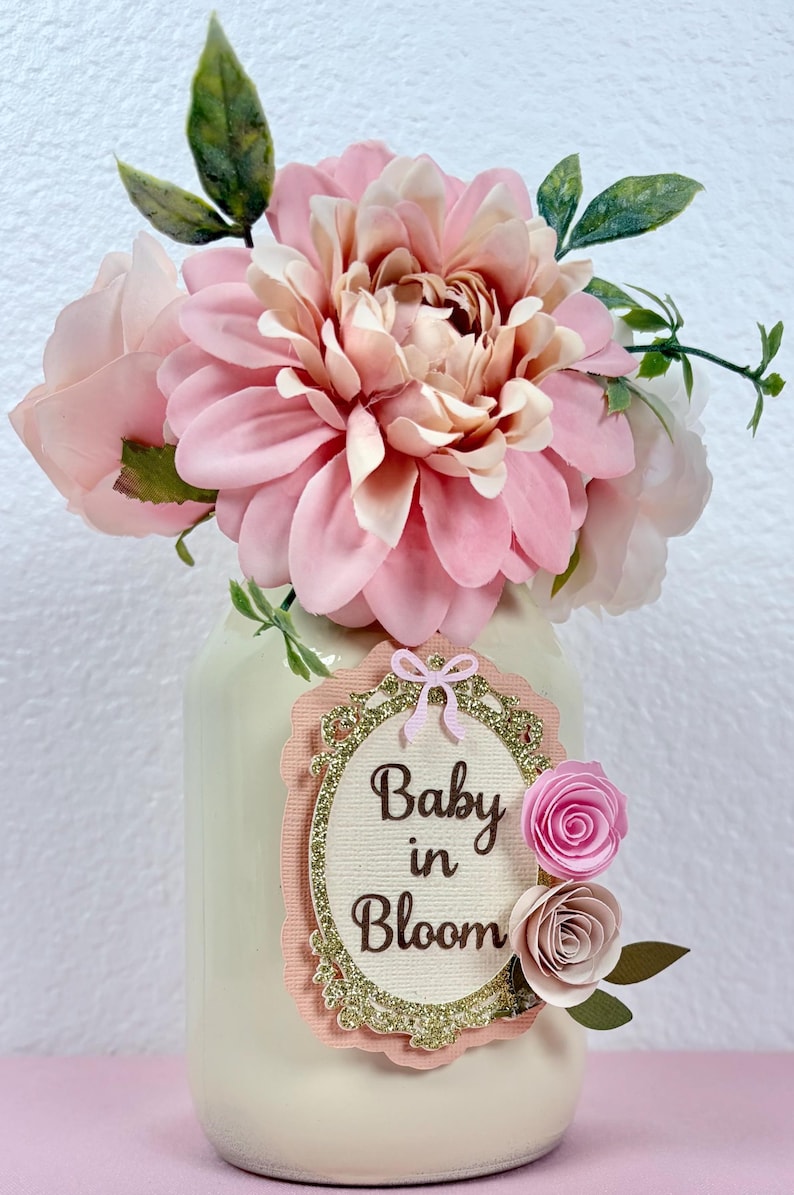 baby in bloom mason jar centerpiece with pink flowers and layered floral baby shower decoration