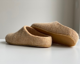 May include: A pair of beige wool slippers with a simple design. The slippers are made of a soft, fuzzy material and have a comfortable fit.
