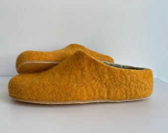 May include: A pair of mustard yellow wool slippers. The slippers are made of a soft, fuzzy material and have a simple, comfortable design.