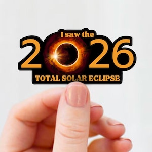 May include: A sticker with the text "I saw the 2026 TOTAL SOLAR ECLIPSE." The design features the numbers 2026 in gold with a black outline, and a circular solar eclipse graphic in the center.