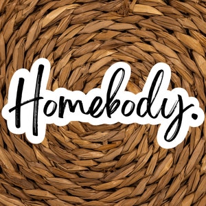 Pu&ograve; includere: La parola "Homebody" scritta in corsivo nero su uno sfondo bianco, con uno sfondo in vimini intrecciato marrone.