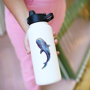 Op de afbeelding: Een witte waterfles met een zwarte dop en een blauwe walvishaai-sticker aan de zijkant.