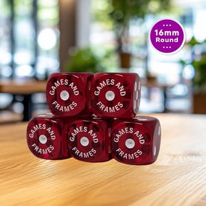 May include: A stack of six translucent red dice with white pips. Each die has the words "GAMES AND FRAMES" printed on one face. A purple circle indicates the dice are 16mm round.