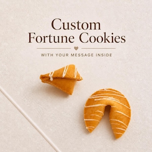 May include: Two golden-brown fortune cookies drizzled with white icing, one folded and one curved. The text above reads Custom Fortune Cookies with a small heart icon and the phrase WITH YOUR MESSAGE INSIDE in dark brown lettering.