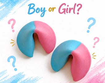 May include: Two fortune cookies dipped in blue and pink icing, positioned below the text Boy or Girl? surrounded by blue and pink question marks and watercolor-style brush strokes in blue and pink on a white background.