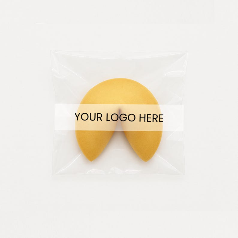 May include: A golden-yellow fortune cookie in a clear plastic wrapper. The cookie has a curved shape, with the text "YOUR LOGO HERE" printed on a white band across the center. The background is plain white.