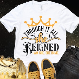 May include: White t-shirt with the text "THROUGH IT ALL she REIGNED" in black and gold lettering, with a gold crown design above the text. The shirt is paired with black jeans and yellow and black sneakers. A gold purse is visible.