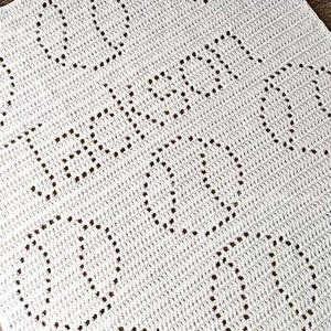 May include: White crocheted blanket with a repeating pattern of hearts. The blanket is made with a fine yarn and has a delicate texture.